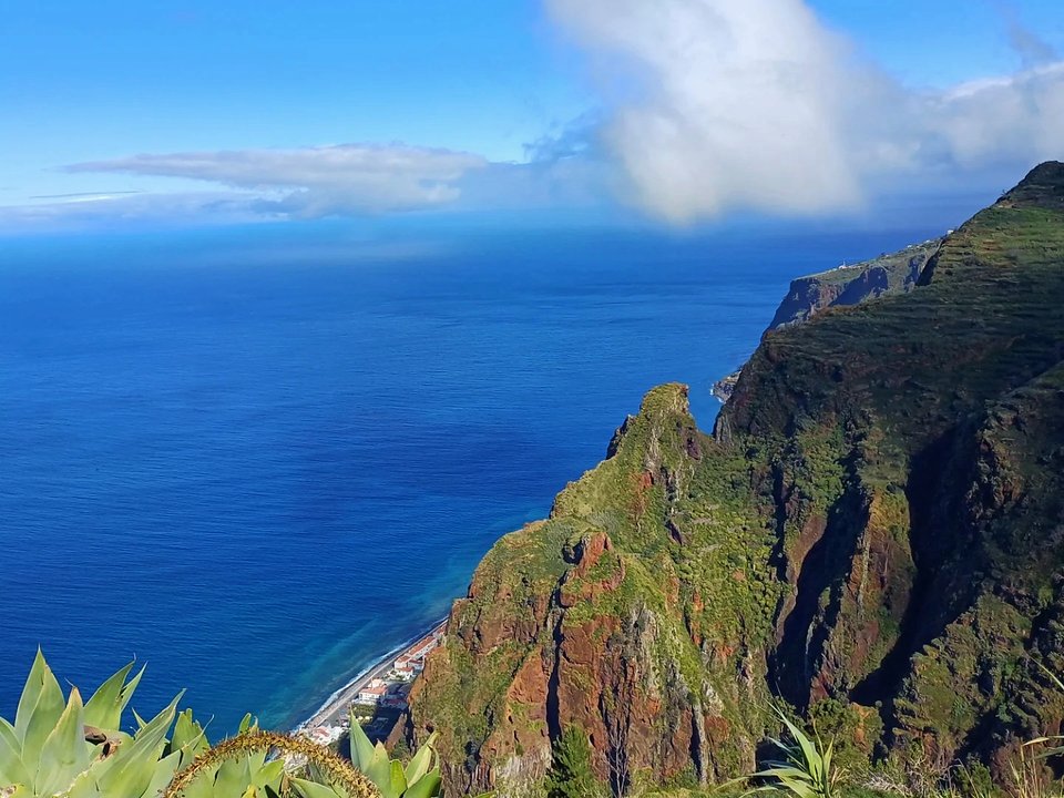 Flat peaceful irrigation channel trail contouring above the sunny coastline of Calheta