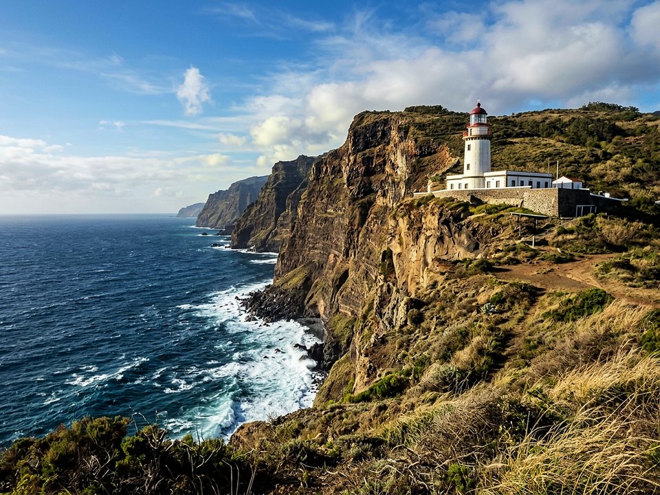 Historic white lighthouse standing atop 300-meter sheer coastal cliffs at Ponta do Pargo