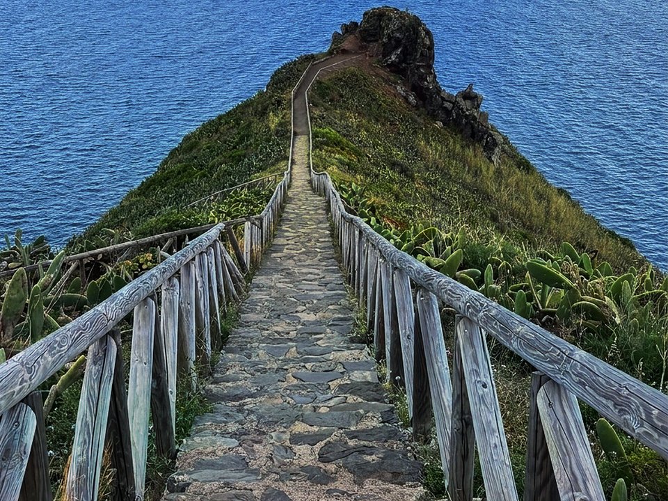 Wooden steps and dramatic narrow coastal ridge leading out to Ponta do Clérigo in Santana