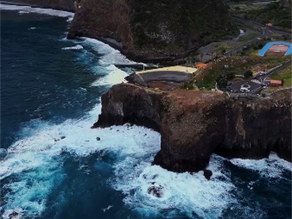Sheer vertical basalt cliffs and deep turquoise ocean waters surrounding the headland
