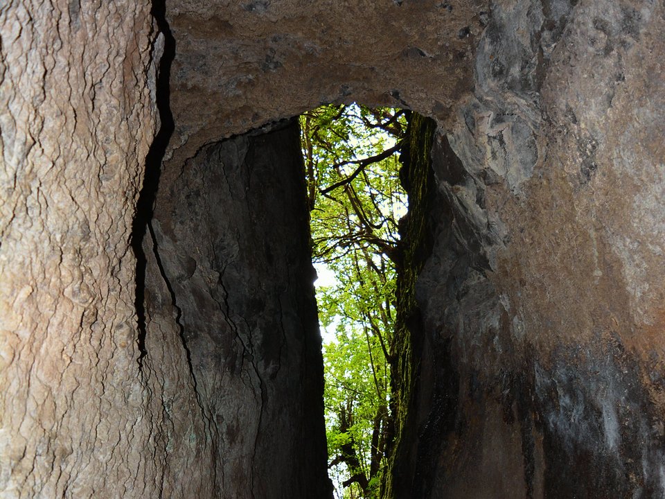Narrow stone slab bridge and railed levada ledge beside a mossy basalt outcrop on PR 10 Levada do Furado