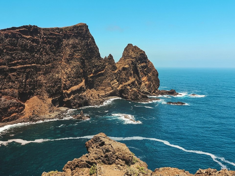 Vibrant ochre and reddish volcanic rock strata above the Atlantic on PR 8