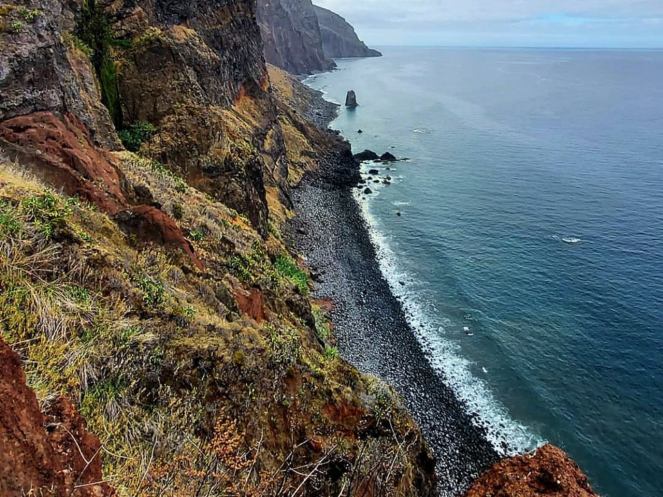 Dramatic coastal trail descending precipitous sea cliffs toward Fajã Grande in Calheta