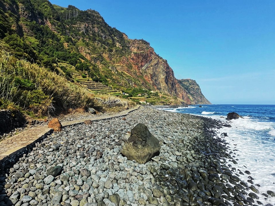 Ocean waterfalls and coastal poios at the base of the towering cliffs of Rocha do Navio