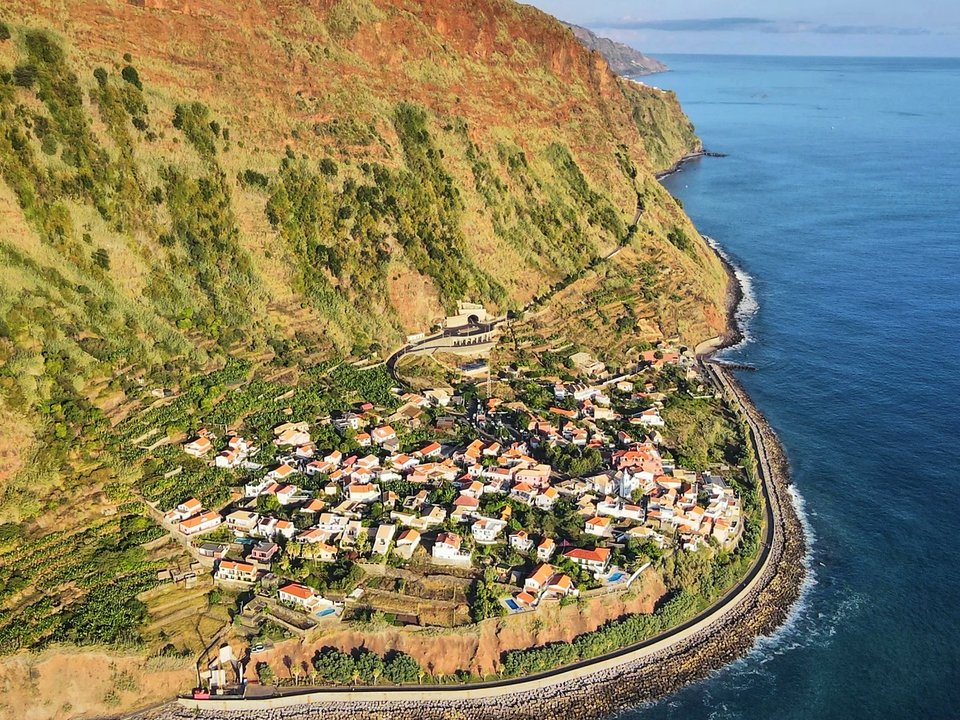 Golden afternoon sunlight illuminating the coastal bluffs and ocean waves at Jardim do Mar